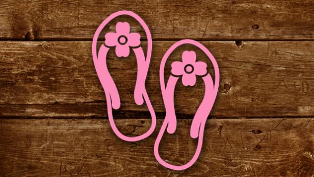 Ein Paar rosa Flip-Flops mit Blumenmuster auf einem Holztisch.