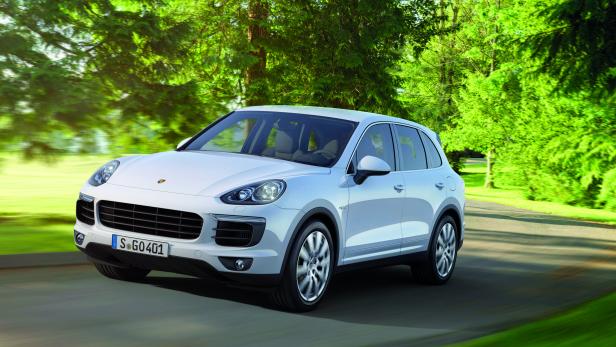 Ein weißer Porsche Cayenne fährt auf einer Landstraße.