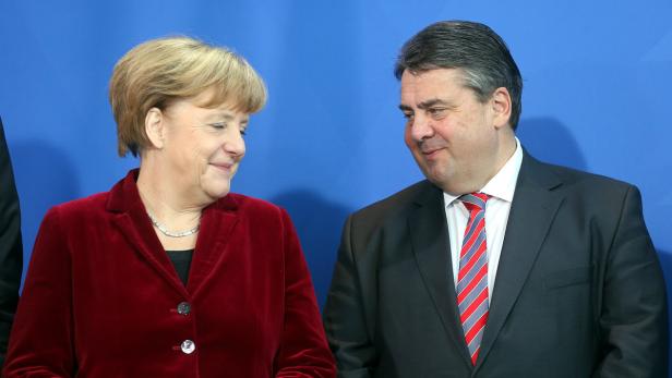 Angela Merkel und Sigmar Gabriel stehen vor einem blauen Hintergrund.
