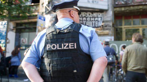 Ein Polizist steht mit dem Rücken zur Kamera in einer städtischen Umgebung.