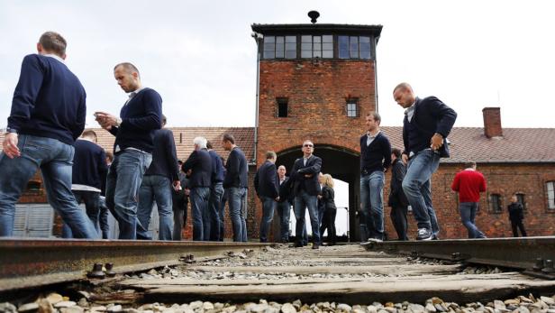 Besucher stehen auf den Gleisen vor dem Tor von Auschwitz-Birkenau.