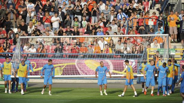 Eine Fußballmannschaft betritt vor einem Publikum das Spielfeld durch ein Tor.