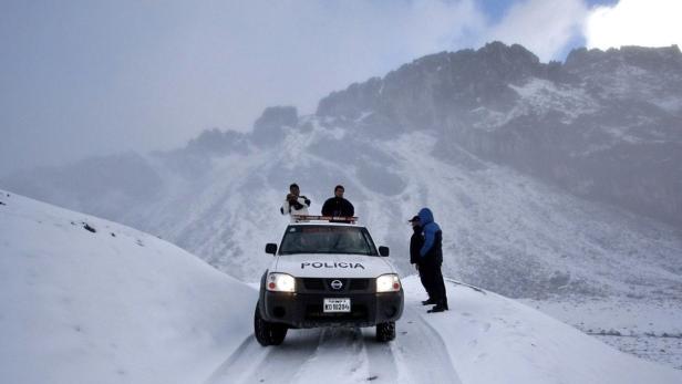 Ein Polizeiwagen steht in einer verschneiten Berglandschaft.