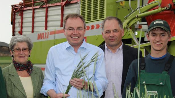 Eine Gruppe von Menschen steht vor einer landwirtschaftlichen Maschine.