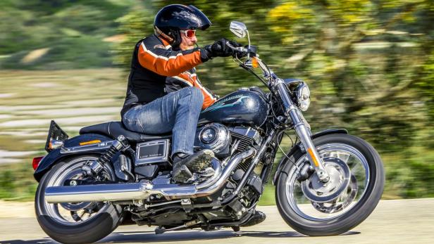 Ein Mann fährt mit einer Harley-Davidson Low Rider auf einer Landstraße.
