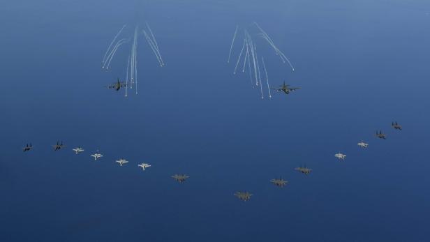 Mehrere Militärflugzeuge fliegen in Formation über dem Meer.
