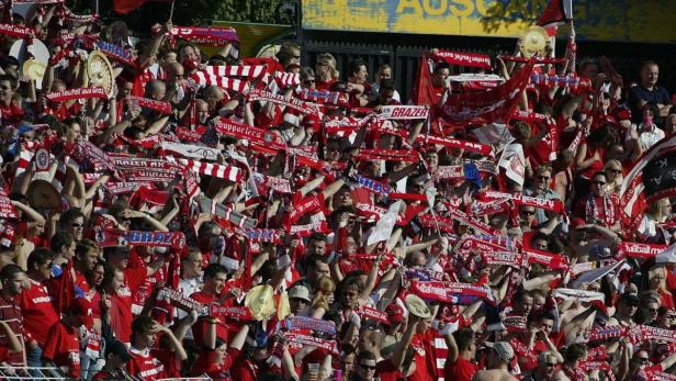 Eine große Menschenmenge, vermutlich Fans des Grazer AK, hält Schals und Fahnen hoch.