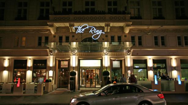 Das Hotel „The Ring“ in Wien bei Nacht mit einem Taxi davor.