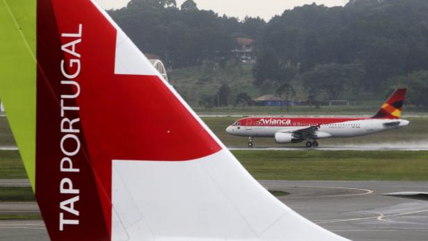 Eine TAP Portugal Flugzeugflosse im Vordergrund, im Hintergrund eine Avianca-Maschine auf der Startbahn.