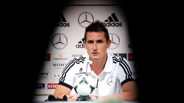 Ein Mann im Deutschland-Trikot sitzt an einem Tisch mit einem Fußball.