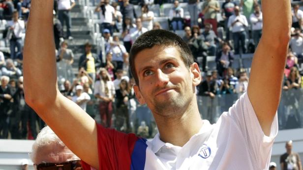 Novak Đoković jubelt mit erhobenen Armen vor einer Zuschauermenge.