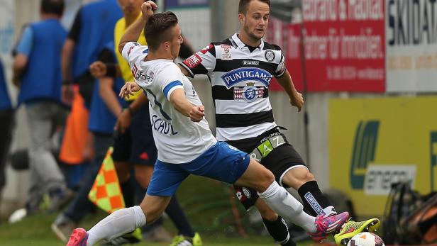Zwei Fußballspieler kämpfen um den Ball während eines Spiels.