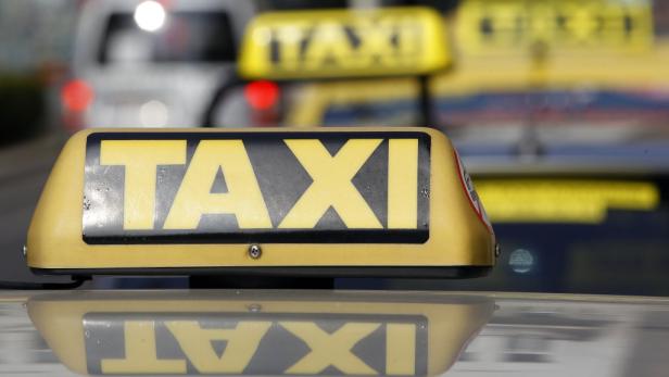 Nahaufnahme eines gelben Taxi-Schilds auf dem Dach eines Autos.