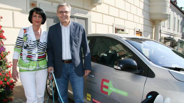Ein Mann und eine Frau stehen vor einem Elektroauto mit dem Slogan „Eisenstadt mobilisiert“.