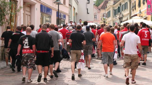 Eine Menschenmenge geht eine Straße entlang, viele tragen rote Kleidung.