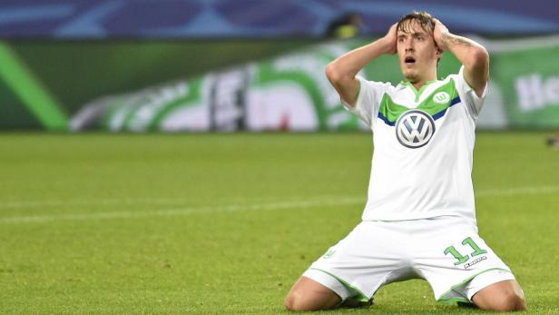 Ein Fußballspieler kniet auf dem Rasen und hält sich die Hände an den Kopf.