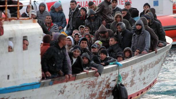 Ein überfülltes Boot mit Menschen, möglicherweise Flüchtlinge, auf dem Meer.