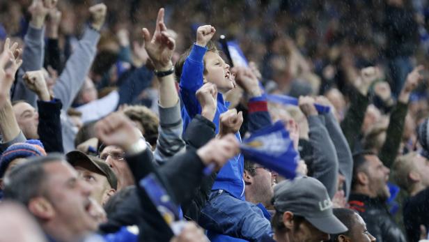 Ein Junge sitzt auf den Schultern eines Mannes und jubelt mit anderen Fans.
