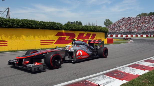 Ein Formel-1-Rennwagen fährt auf einer Rennstrecke an einer gelben Wand mit dem DHL-Logo vorbei.