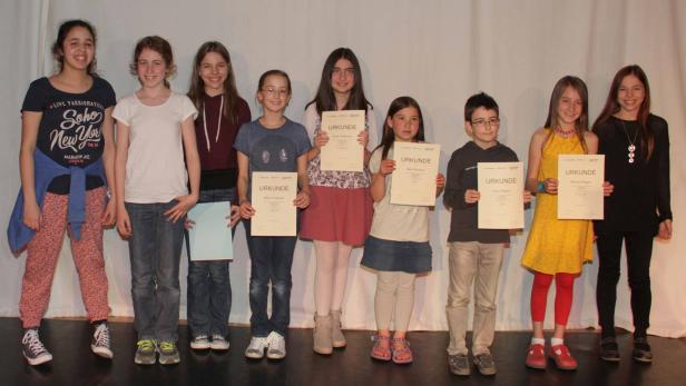 Eine Gruppe von Kindern steht mit Urkunden auf einer Bühne.