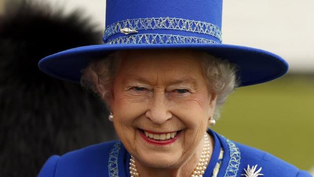 Ein Porträt von Königin Elizabeth II. mit einem strahlenden Lächeln und einem blauen Hut.