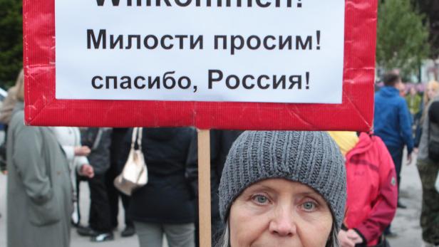 Eine Frau hält ein Schild mit der Aufschrift „Herzlich Willkommen! Милости просим! спасибо, Россия!“.