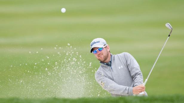 Ein Golfspieler schlägt einen Ball aus einem Sandbunker.