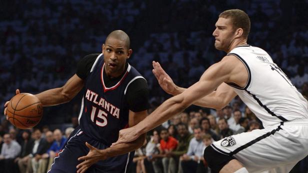 Ein Basketballspieler der Atlanta Hawks dribbelt den Ball, während ein Gegenspieler ihn zu verteidigen versucht.
