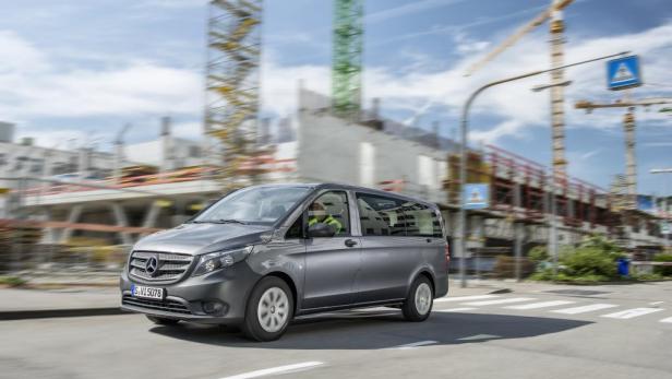 Ein grauer Mercedes-Benz Vito fährt auf einer Straße an einer Baustelle vorbei.