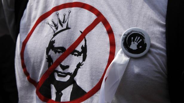 Auf einem T-Shirt ist ein durchgestrichenes Porträt von Putin mit einer Krone zu sehen.