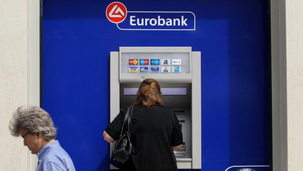 Eine Frau benutzt einen Geldautomaten der Eurobank.