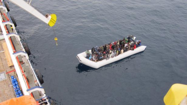 Ein überfülltes Schlauchboot treibt auf dem offenen Meer.