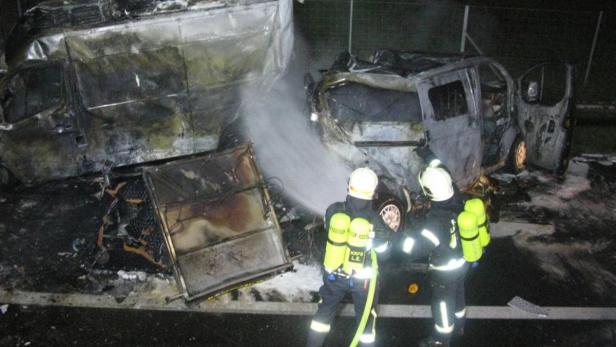Feuerwehrleute löschen zwei ausgebrannte Transporter.