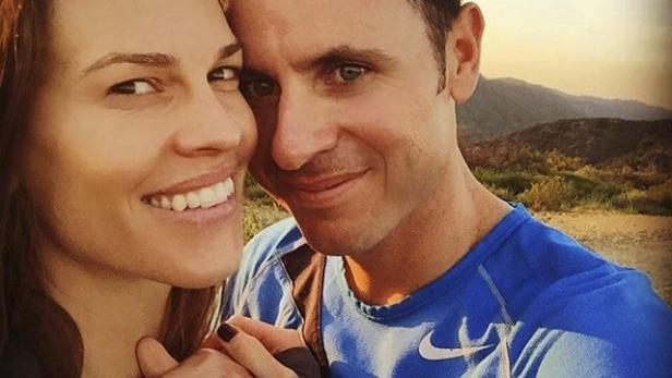 Hilary Swank und ihr Ehemann posieren vor einer Berglandschaft.