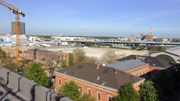 Blick über eine Stadtlandschaft mit Backsteingebäuden, einer Baustelle und einer Autobahnbrücke.