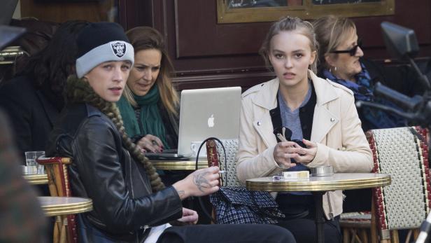 Lily-Rose Depp sitzt mit Freunden in einem Café in Paris.