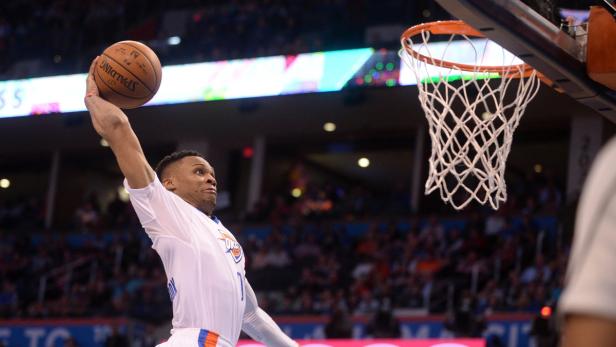 Ein Basketballspieler springt, um den Ball in den Korb zu werfen.