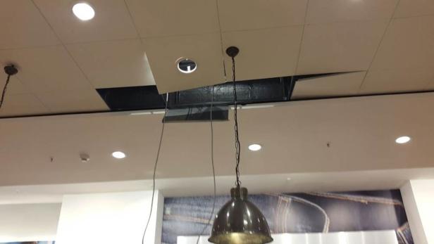 Eine Deckenplatte hat sich gelöst und gibt den Blick auf die Installationen frei.