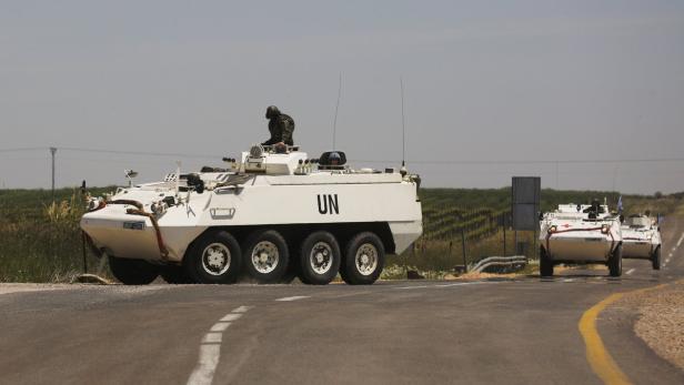 Mehrere weiße UN-Fahrzeuge fahren auf einer asphaltierten Straße.