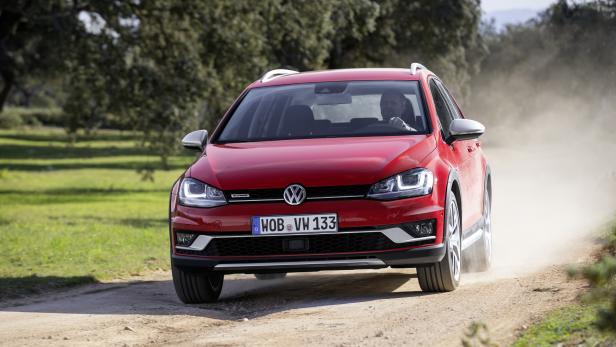 Ein roter VW Golf Alltrack fährt auf einer unbefestigten Straße.