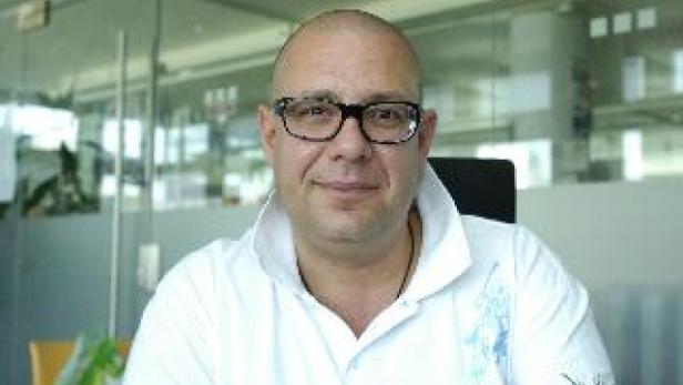 Ein Mann mit Brille und weißem Hemd sitzt an einem Tisch.