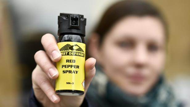 Eine Frau hält eine Dose Pfefferspray der Marke „First Defense“ in der Hand.