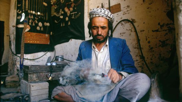 Ein Mann mit Turban lötet in seiner Werkstatt Schmuck.
