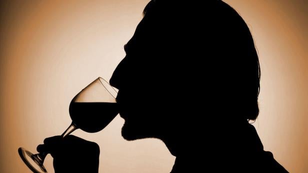 Die Silhouette eines Mannes, der ein Glas Wein trinkt.