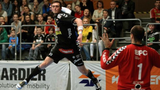 Ein Handballspieler springt, um einen Ball auf das Tor zu werfen.