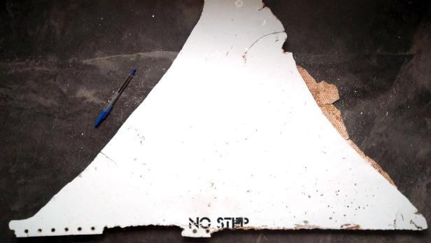 Ein beschädigtes, dreieckiges Flugzeugteil mit der Aufschrift „NO STEP“ liegt auf dem Boden.