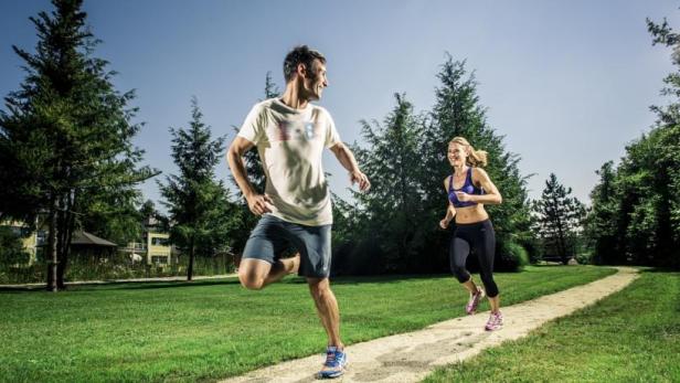 Ein Mann und eine Frau joggen auf einem Pfad in einem Park.