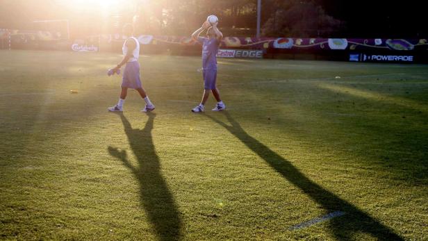 Zwei Fußballspieler trainieren auf einem sonnigen Rasenplatz.