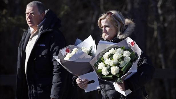 Eine Frau und ein Mann tragen jeweils einen Strauß weißer Rosen.