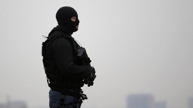 Ein Polizist mit Sturmhaube und Schutzweste steht aufmerksam da.